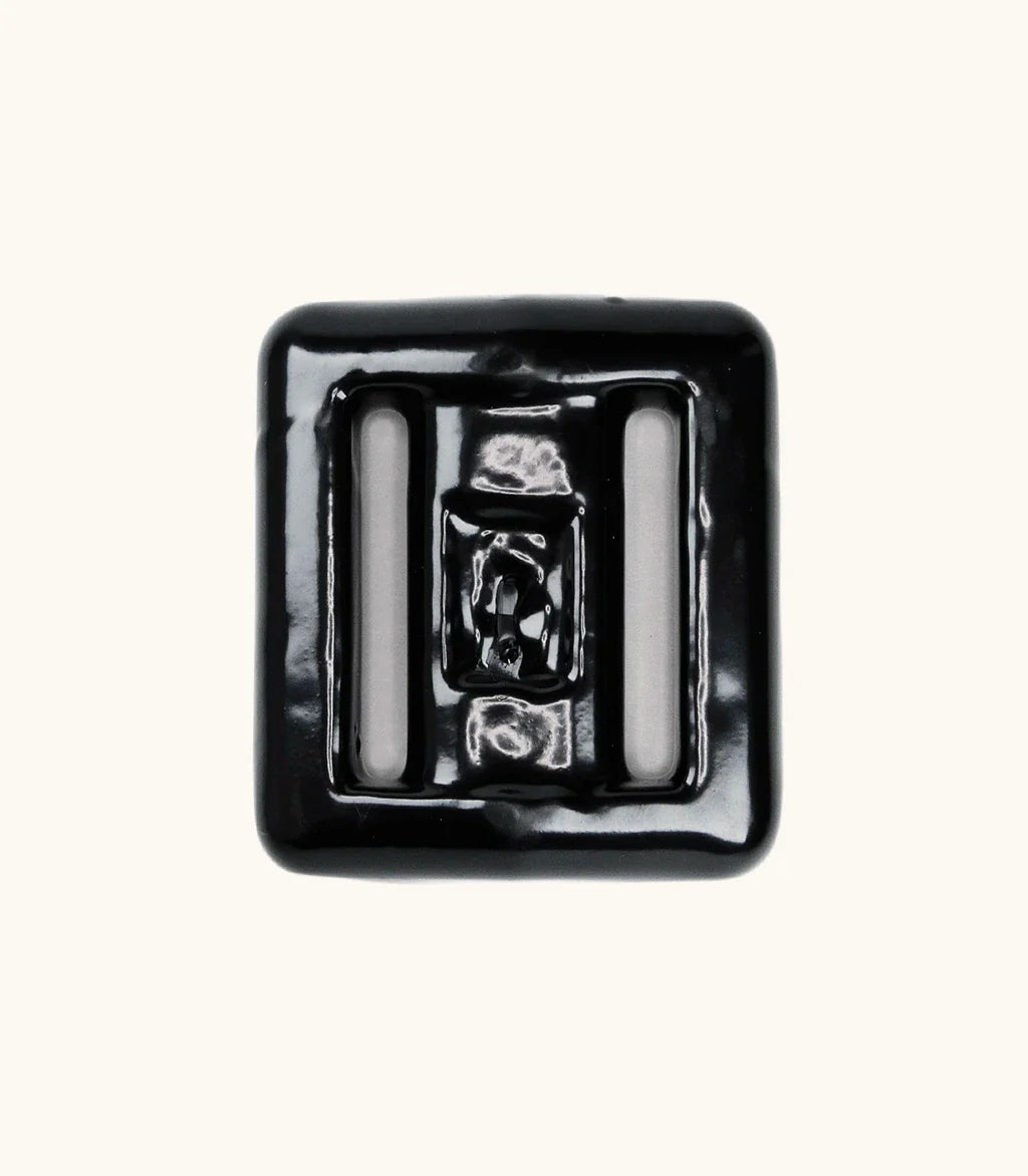 Black rubber-coated lava rock dive weight with two strap slots, photographed from above on a light background.
